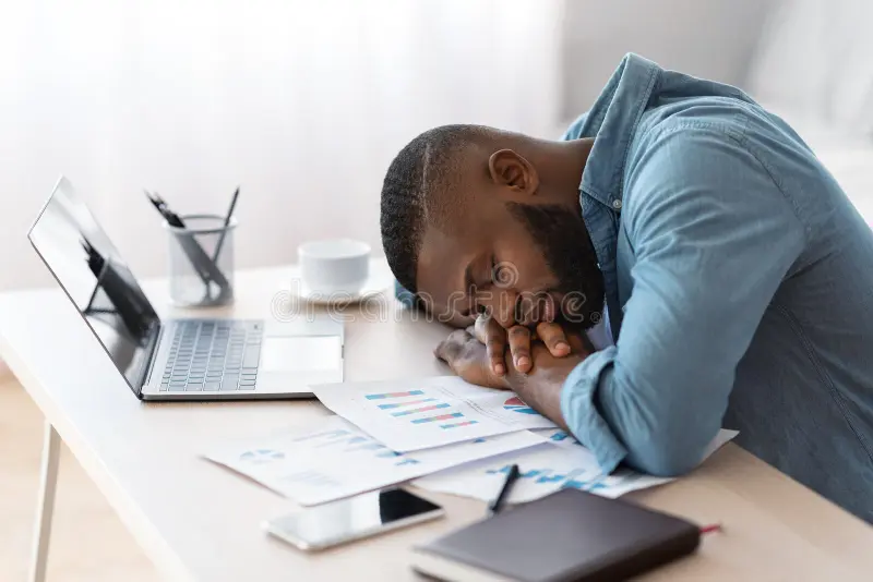 WHY YOU FEEL TIRED EVEN WHEN YOU’RE NOT DOING “MUCH” tired african american freelancer guy sleeping desk laptop papers tired african american freelancer guy sleeping 213438171